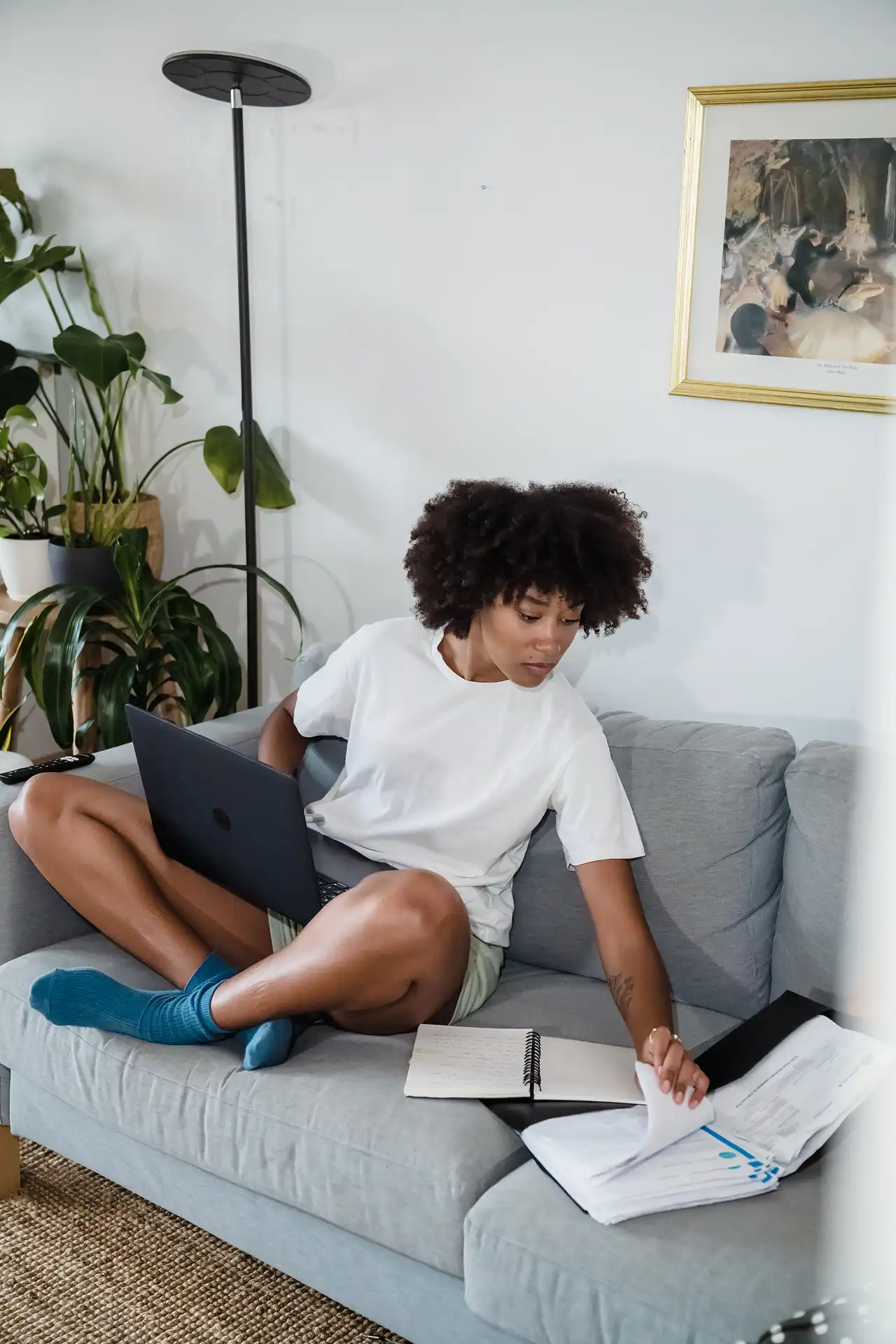 a person sitting on sofa working on a laptop and some books